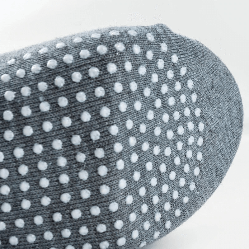 Close-up of grey sports anti-slip sock with white massage dots for comfort and grip. Breathable unisex cotton socks for active wear.